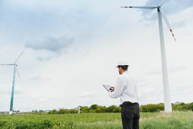 Ingénieur masculin avec un casque travaillant à la ferme éolienne sur tablette