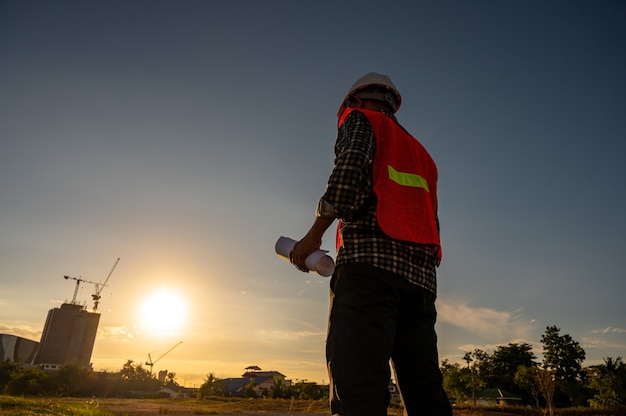 Ingénieur masculin travaillant sur le chantier de construction à l'heure du coucher du soleil de Silhouette