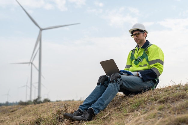 Ingénieur masculin utilisant un ordinateur portable pour l'inspection des éoliennes dans les parcs éoliens pour générer de l'énergie renouvelable