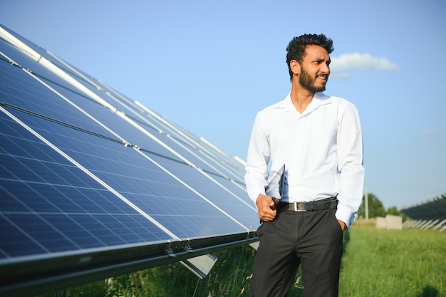 un ingénieur masculin vérifie une centrale solaire photovoltaïque et utilise une tablette d'enregistrement un homme indien en uniforme tenant une tablette