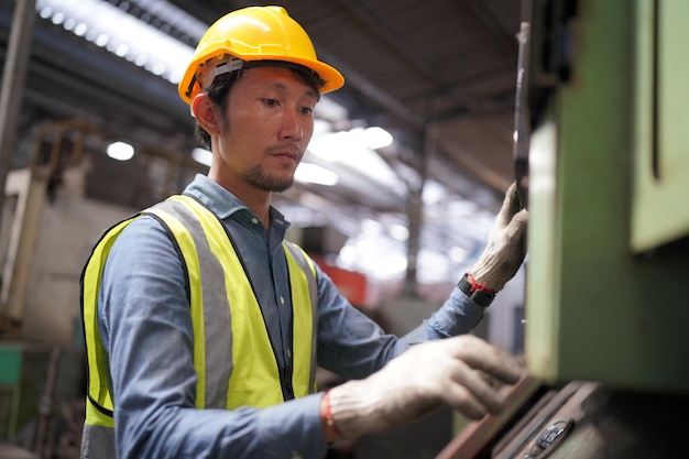 Ingénieur métallurgiste opérateur industriel expérimenté technicien ouvrier dans un casque de sécurité travaillant sur une machine de tour, homme professionnel dans l'atelier d'usine de fabrication de technologie industrielle