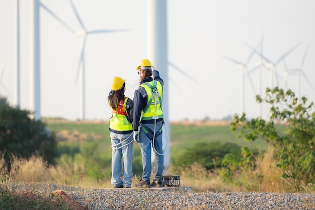 Un ingénieur et un ouvrier discutent sur un parc d'éoliennes avec des plans