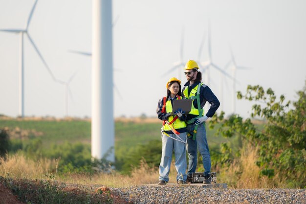 Un ingénieur et un ouvrier discutent sur un parc d'éoliennes avec des plans