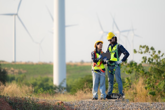 Un ingénieur et un ouvrier discutent sur un parc d'éoliennes avec des plans