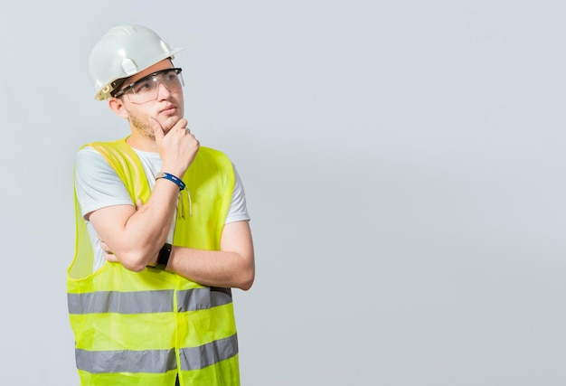 Un ingénieur pensif sur fond blanc Concept d'un ingénieur méditatif solated Pensive builder man with hand on chin Portrait of young builder thinking with hand on menton isolated