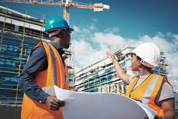 Ingénieur de plan directeur ou équipe d'architectes parlant en plein air de la construction ou de l'architecture d'un projet de construction