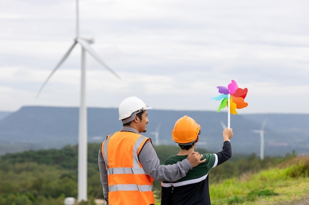 Ingénieur progressiste avec son fils tenant un jouet de moulin à vent dans la montagne