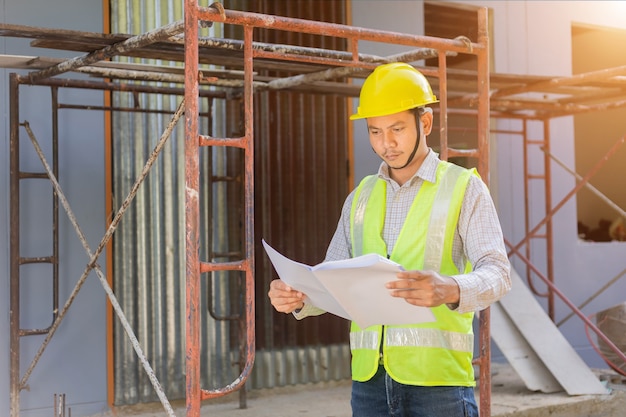 Un ingénieur regarde le plan d'étage sur le chantier de construction.