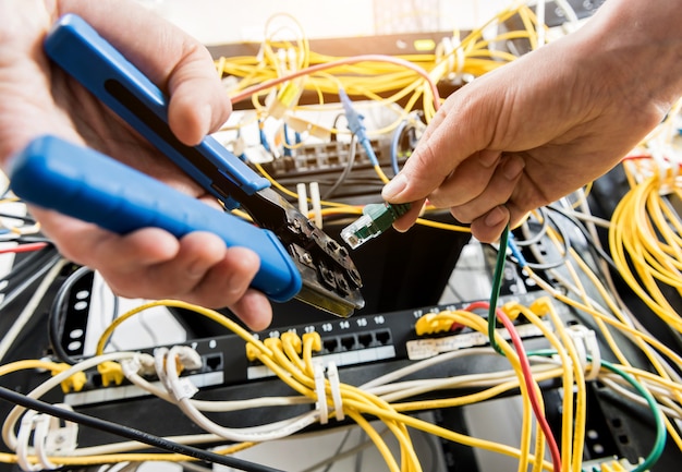 Ingénieur Réseau Travaillant Dans La Salle Des Serveurs. Connexion Des Câbles Réseau Aux Commutateurs