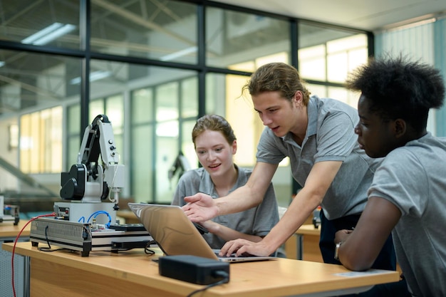 Ingénieur en robotique en stage apprenant avec la main robotique de programmation et de manipulation