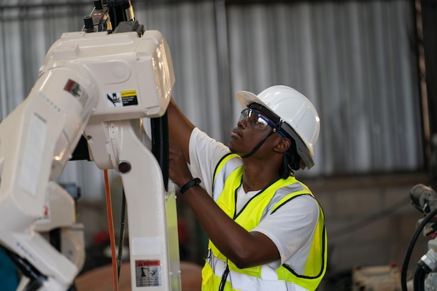 Ingénieur en robotique travaillant sur la maintenance d'un bras robotique moderne dans un entrepôt d'usine
