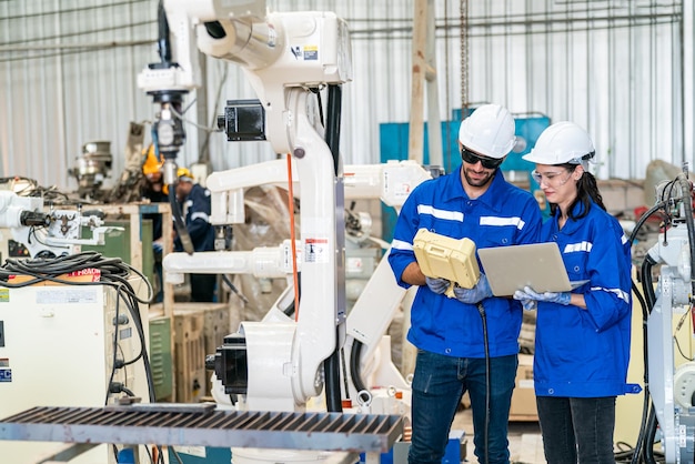 Ingénieur en robotique travaillant sur la maintenance d'un bras robotique moderne dans un entrepôt d'usine