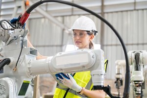 Photo ingénieur en robotique travaillant sur la maintenance d'un bras robotique moderne dans un entrepôt d'usine