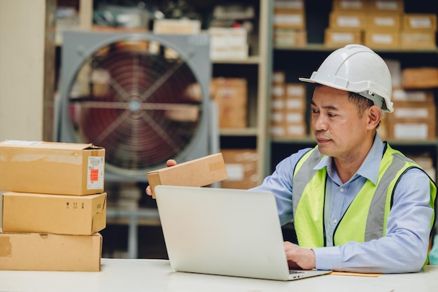 Ingénieur senior masculin vérifiant la boîte d'inventaire travailleur de stock à la recherche de pièces de produits pour l'expédition