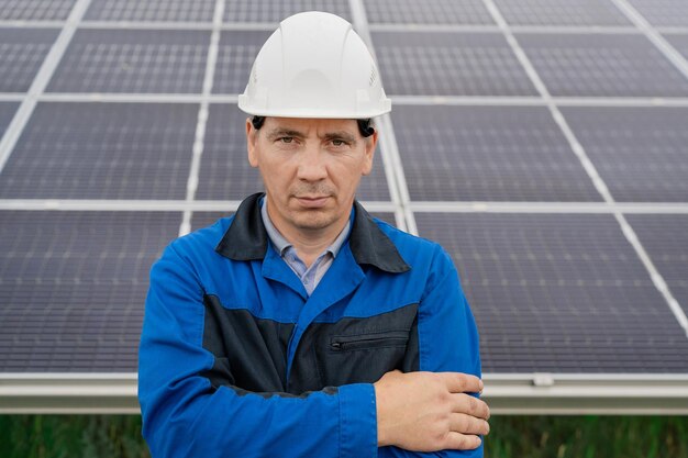 Ingénieur de service homme debout avec les bras croisés devant les panneaux solaires technicien de maintenance