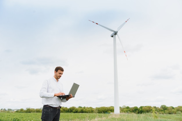 Ingénieur de sexe masculin travaillant à la ferme éolienne sur ordinateur portable