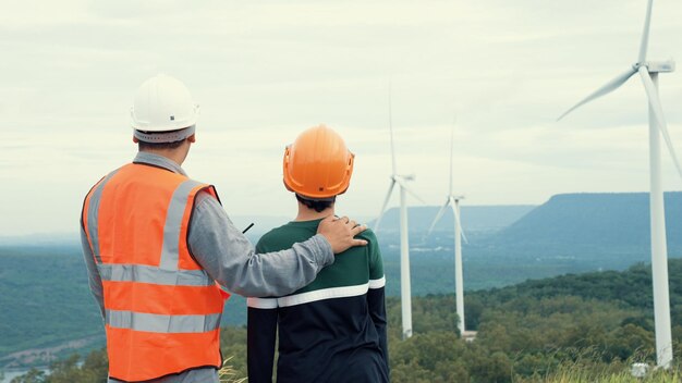 Ingénieur avec son fils sur un parc éolien au sommet d'une colline ou d'une montagne en milieu rural Idéal progressiste pour la production future d'énergie renouvelable et durable Production d'énergie à partir d'une éolienne