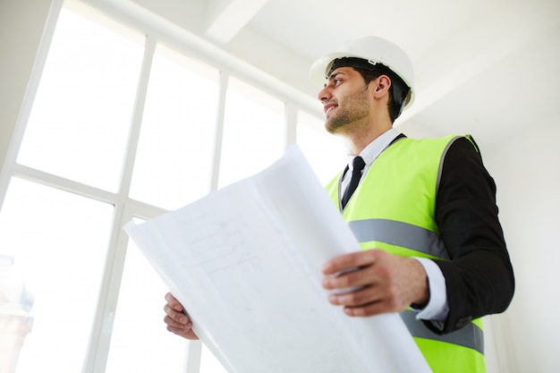 Ingénieur souriant tenant des plans