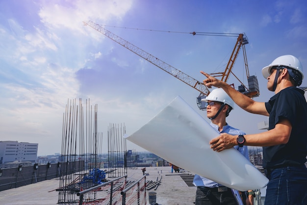 L'ingénieur en structure et le contremaître avec des plans discutent de l'inspection du bâtiment extérieur