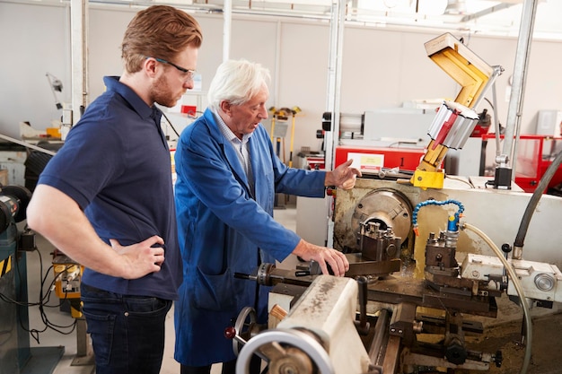 Ingénieur supérieur instruisant l'apprenti au banc de machine