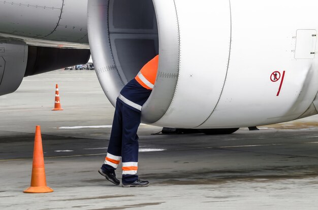 Photo ingénieur technicien humain vérifie la pale de l'avion du moteur à turbine après le voyage et psodki dans le parking de l'aéroport.