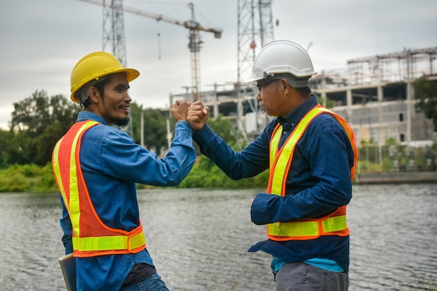 Ingénieur de travail d'équipe et poignée de main d'homme d'affaires au chantier de construction