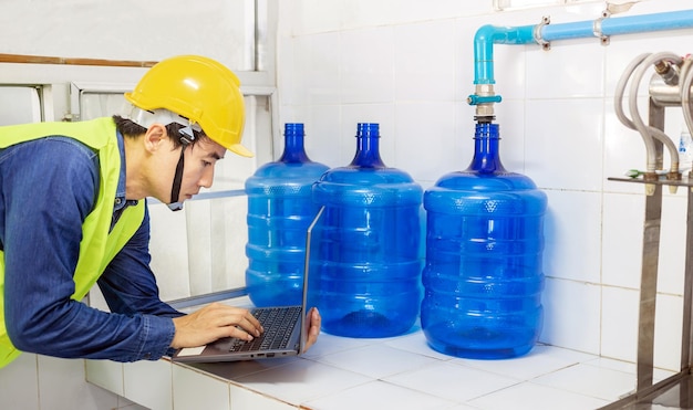 Ingénieur travaillant dans une usine d'eau potable à l'aide d'un ordinateur tablette pour vérifier et réparer l'eau de la chaudière