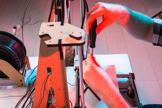 Ingénieur travaillant la nuit dans le laboratoire, il ajuste les composants d'une imprimante.