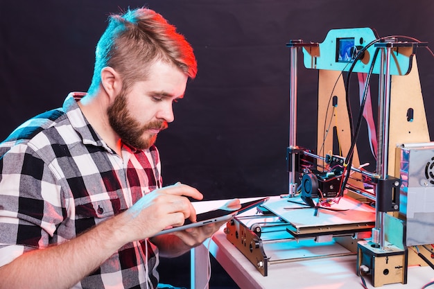 Ingénieur travaillant la nuit dans le laboratoire, il ajuste les composants d'une imprimante.