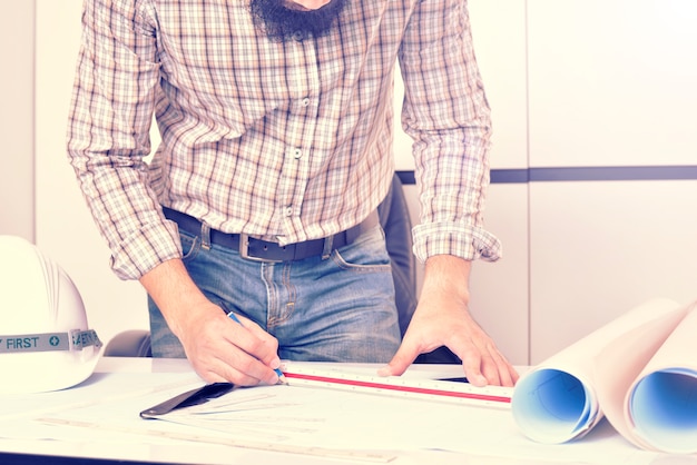 L&#39;ingénieur travaille sur le bureau avec plan de dessin