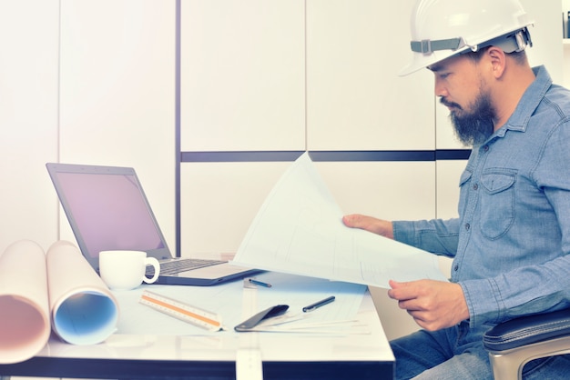 Photo l'ingénieur travaille sur le bureau avec plan de dessin