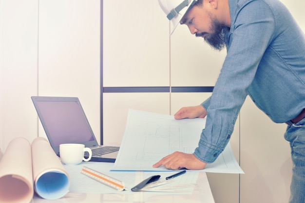 L&#39;ingénieur travaille sur le bureau avec plan de dessin