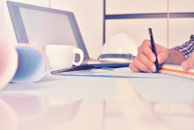 L&#39;ingénieur travaille sur le bureau avec plan de dessin