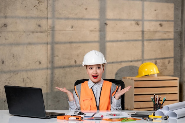 Ingénieur travailleur civil en casque et gilet smart jeune fille blonde mignonne agitant les mains