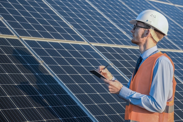 Ingénieur en uniforme debout sur un des panneaux solaires