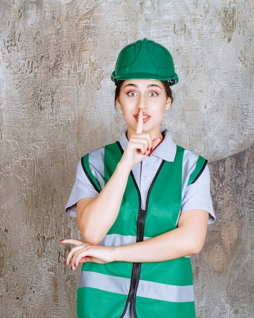 Ingénieur en uniforme vert et casque demandant de ne rien dire.