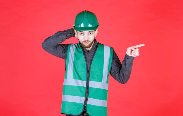 Ingénieur en uniforme vert et casque montrant le côté droit.