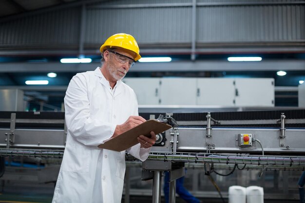 Ingénieur d'usine conservant des enregistrements sur le bloc-notes de l'usine