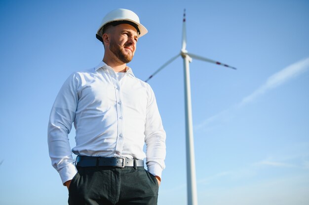 L'ingénieur vérifie la production d'énergie sur l'éolienne. Travailleur dans le parc des moulins à vent en casque.