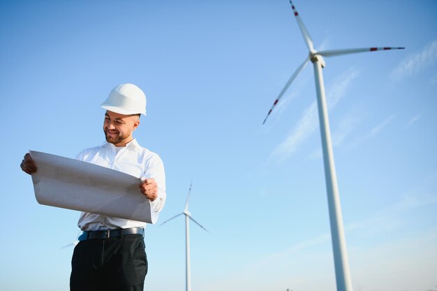 L'ingénieur vérifie la production d'énergie sur l'éolienne. Travailleur dans le parc des moulins à vent en casque.