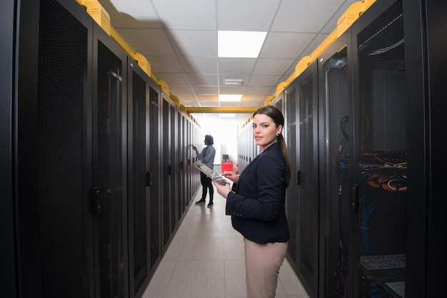 Photo ingénieure informatique travaillant sur une tablette dans une salle serveur d'un centre de données moderne