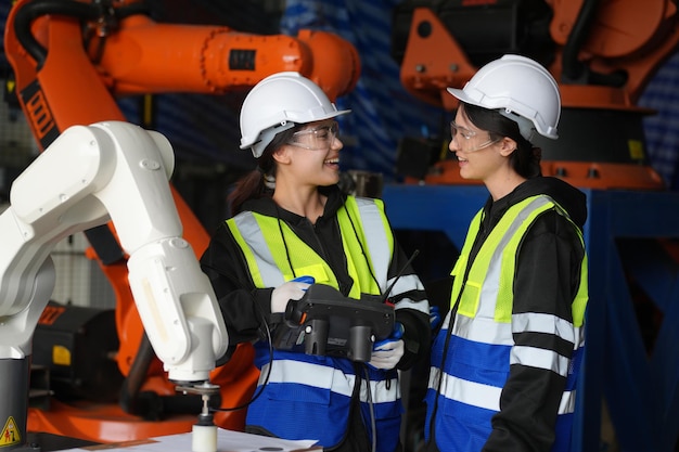 Une ingénieure vérifie et contrôle la machine de bras de robot d'automatisation dans une usine intelligente industrielle sur la robotique logicielle du système de surveillance en temps réel et l'opération de fabrication numérique