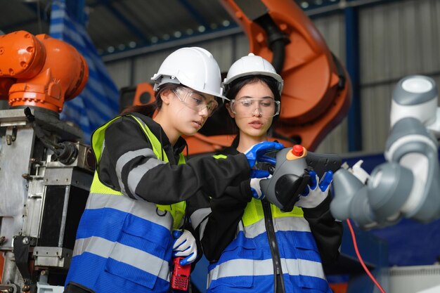 Une ingénieure vérifie et contrôle la machine de bras de robot d'automatisation dans une usine intelligente industrielle sur la robotique logicielle du système de surveillance en temps réel et l'opération de fabrication numérique