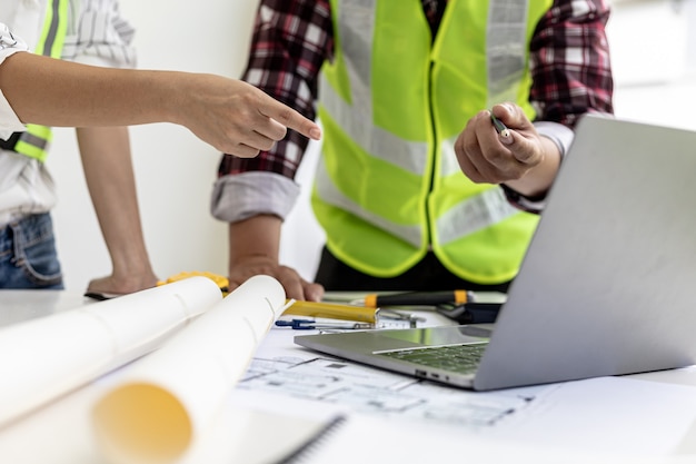 Ingénieurs et architectes pointant vers des écrans d'ordinateurs portables regardant des plans pour apporter quelques modifications, ils se réunissent pour planifier la construction et les correctifs. Idées de design et de design d'intérieur.