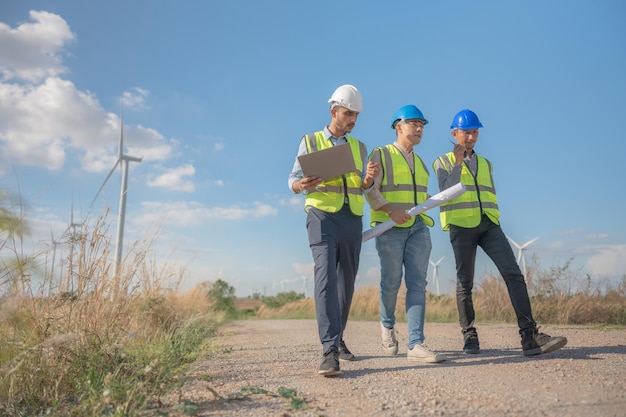 Ingénieurs asiatiques travaillant sur le terrain en plein air Travailleurs marchant et inspectant la construction et la machine autour du site du projet Éolienne électrique de ressources propres énergétiques et environnementales durables