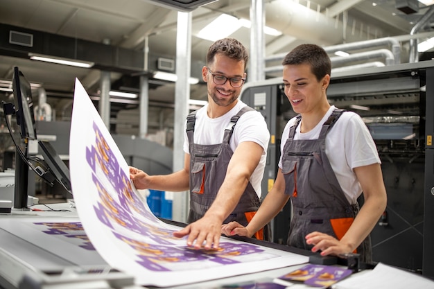 Photo ingénieurs graphiques ou travailleurs vérifiant la qualité de l'impression dans une imprimerie moderne.