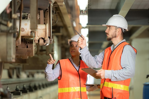 Des ingénieurs et des ingénieuses travaillent ensemble dans une station de réparation électrique pour inspecter le châssis.