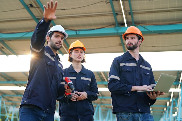 Ingénieurs installant des panneaux solaires sur le toit Ingénieurs masculins marchant le long de rangées de panneaux photovoltaïques