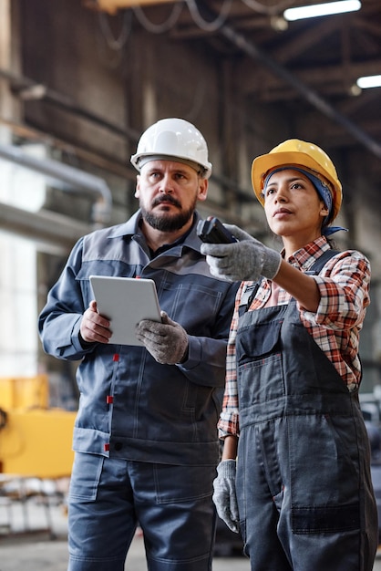 Ingénieurs d'installations industrielles contemporaines travaillant avec d'énormes machines