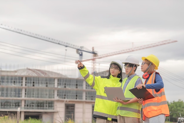 Des ingénieurs jeunes et seniors discutent des travaux d'un grand bâtiment en constructionTrois personnes travaillant sur le site en construction